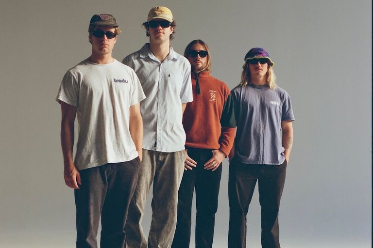 Australian indie surf-rock band Surf Trash posing in streetwear, hats, and sunglasses against a plain studio background for a promo photo shoot.